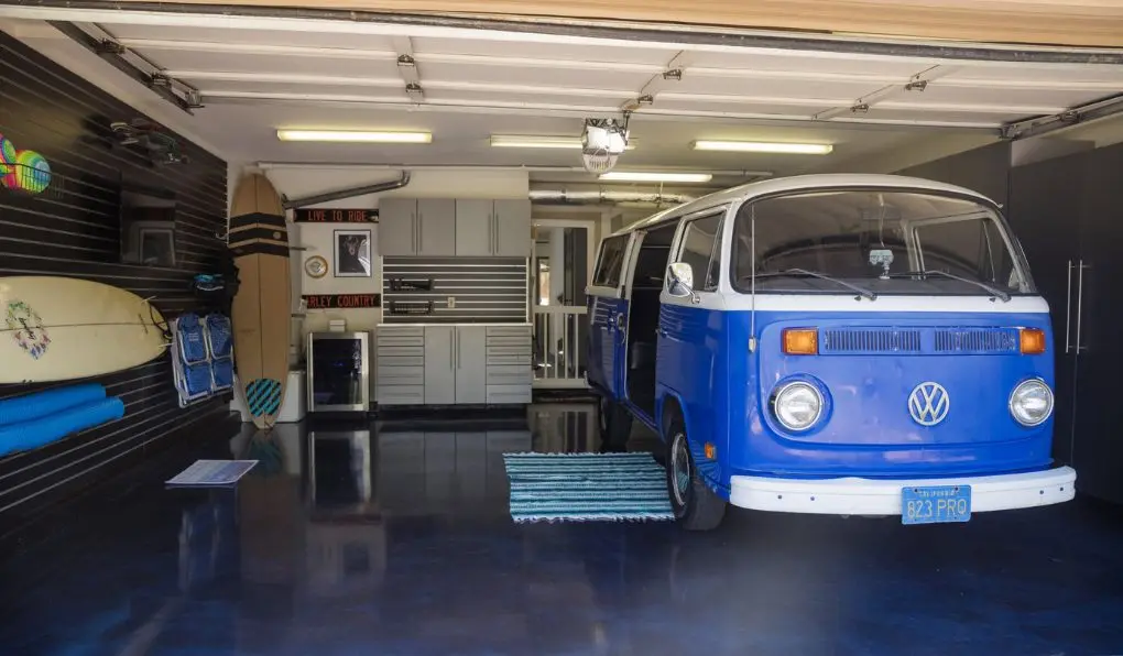 Blue volkswagor parked in a refurbished garage with blue epoxy floor and black slatwall storage solution and black cabinets