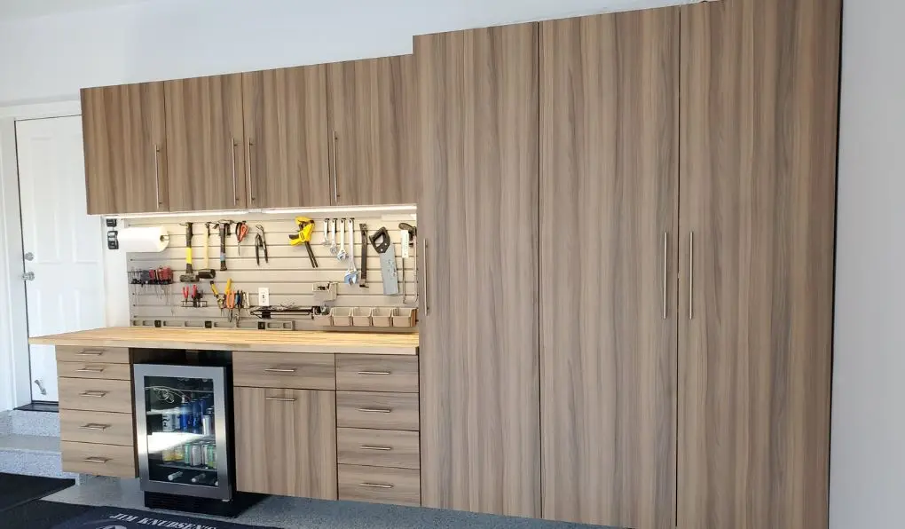 Remodeled garage with wooden cabinets wooden countertop, and beige slat system backsplash
